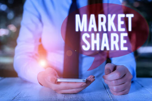 Writing note showing Market Share. Business photo showcasing The portion of a market controlled by a particular company Female business person sitting by table and holding mobile phone.