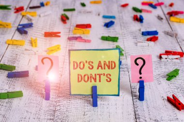 El yazısı metin Do S Ve Dont S. Bazı faaliyet veya eylemler karalama ve ahşap masaya yerleştirilen ataş ile parçalanan levha ile ilgili kurallar veya gümrük anlamı.