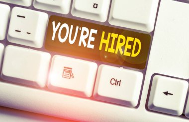 Kavramsal el yazısı You Re Hired gösteren. İş fotoğraf metin Yeni İş İstihdam Newbie Kayıtlı Kabul İşe Beyaz pc klavye beyaz arka plan üzerinde not kağıdı ile.