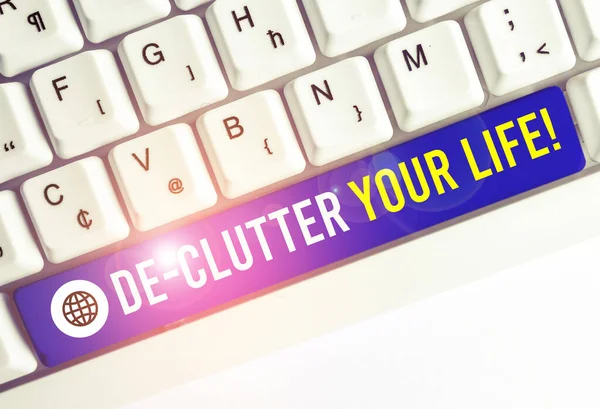 Escribiendo nota mostrando De Clutter Your Life. Exhibición de fotos de negocios eliminar elementos innecesarios de lugares desordenados o hacinados Teclado blanco de PC con papel de nota sobre el fondo blanco . — Foto de Stock