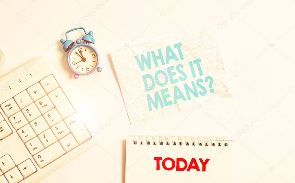 Text sign showing What Does It Means Question. Conceptual photo asking meaning something said and do not understand Blank paper with copy space on the table with clock and pc keyboard.