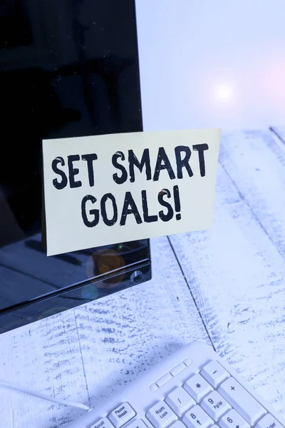 Word writing text Set Smart Goals. Business concept for list to clarify your ideas focus efforts use time wisely Notation paper taped to black computer monitor screen near white keyboard.