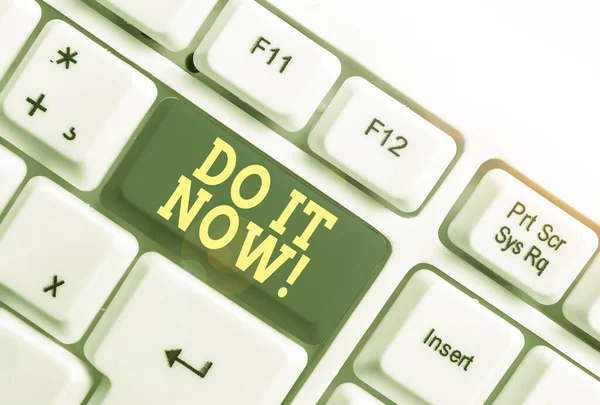 Text sign showing Do It Now. Conceptual photo not hesitate and start working or doing stuff right away White pc keyboard with empty note paper above white background key copy space.