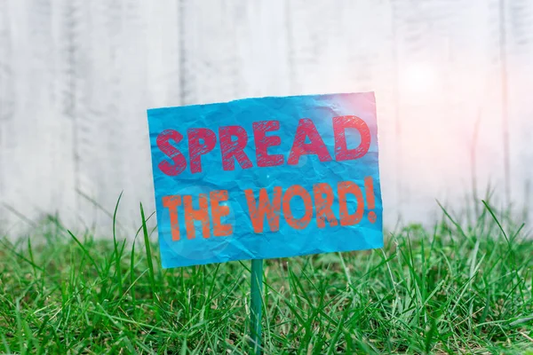 「 Spread The Word 」を示すテキスト記号。概念写真は、ソーシャルメディアを使用して情報やニュースを共有する棒に添付され、緑の草原の土地に配置されたプレーン空の紙. — ストック写真