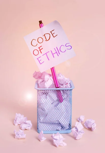Writing note showing Code Of Ethics. Business photo showcasing basic guide for professional conduct and imposes duties crumpled paper and stationary with paper placed in the trash can.