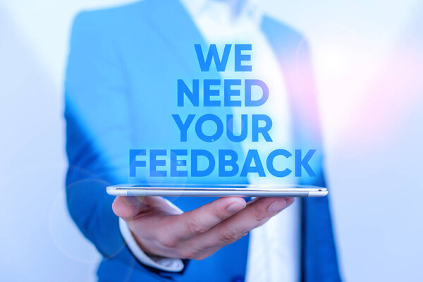 Writing note showing We Need Your Feedback. Business photo showcasing criticism given to say can be done improvement Man in the blue suite and white shirt holds mobile phone in the hand.