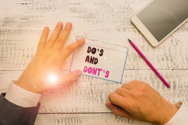 「 Do S 」と「 Don t 」を示す概念的な手書き文字。アクティビティやアクションに関するルールや習慣を紹介するビジネス写真筆記具やスマートフォンの近くでノートを手に取る. — ストック写真