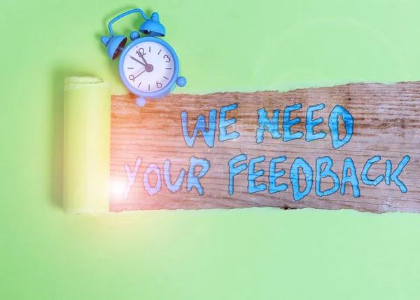 Handwriting text writing We Need Your Feedback. Concept meaning criticism given to say can be done improvement Alarm clock and torn cardboard placed above a wooden classic table backdrop. — Stockfoto