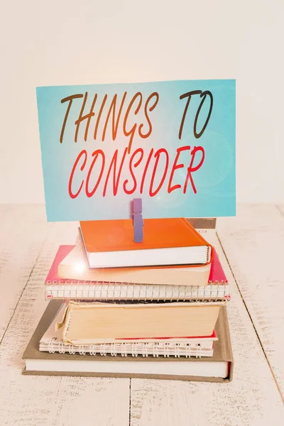 Handwriting text writing Things To Consider. Concept meaning think about carefully especially in making decisions pile stacked books notebook pin clothespin colored reminder white wooden. — Stock Photo, Image