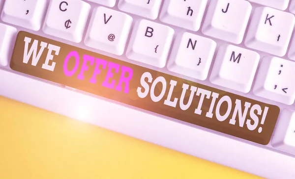 Conceptual hand writing showing We Offer Solutions. Business photo showcasing way to solve problem or deal with difficult situation White pc keyboard with note paper above the white background.