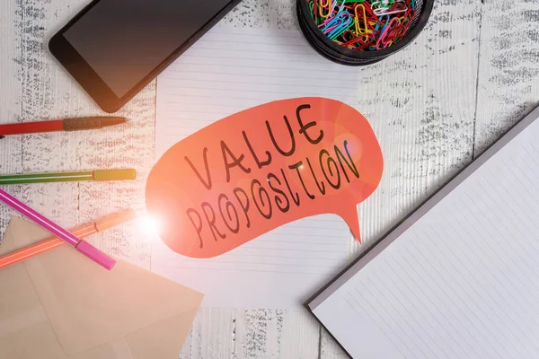 Woordschrijvende tekst Value Proposition. Zakelijk concept voor functie bedoeld om een bedrijf of product aantrekkelijk Smartphone pennen envelop clips spraakbellenvel notebook houten achterkant. — Stockfoto