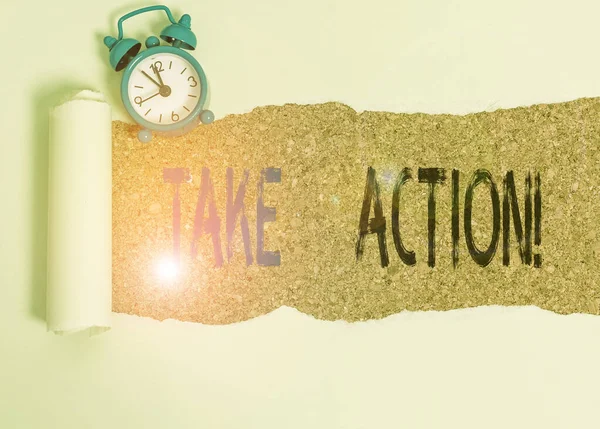 Word writing text Take Action. Business concept for do something official or concerted to achieve aim with problem Alarm clock and torn cardboard placed above a wooden classic table backdrop.