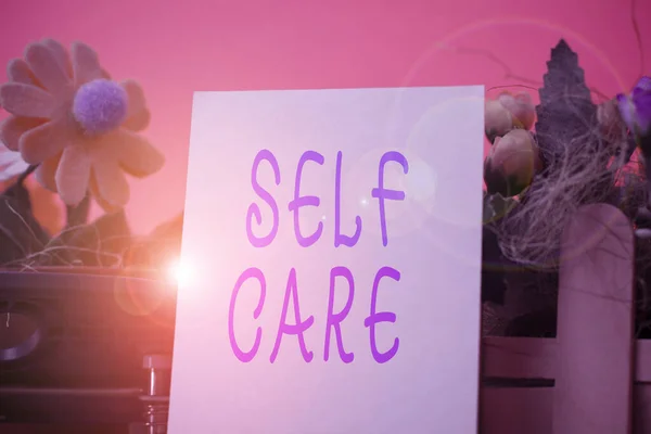 Текст от руки Self Care. Концепция, означающая практику принятия мер по улучшению своего здоровья Цветы и письменное оборудование плюс простой лист выше текстурированного фона . — стоковое фото