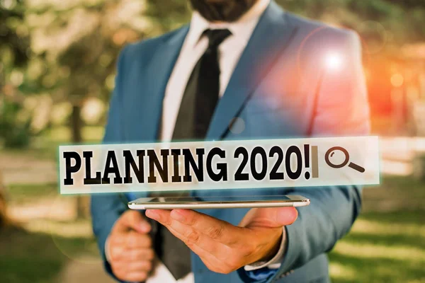 Rukopisný text Plánování2020. Koncept znamená proces tvorby plánů na něco příští rok Podnikatel v modrém apartmá stojí s mobilním telefonem v ruce. — Stock fotografie
