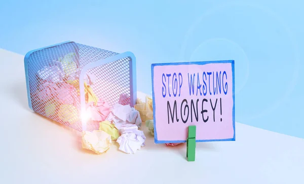 Text sign showing Stop Wasting Money. Conceptual photo advicing demonstrating or group to start saving and use it wisely Trash bin crumpled paper clothespin empty reminder office supplies tipped.