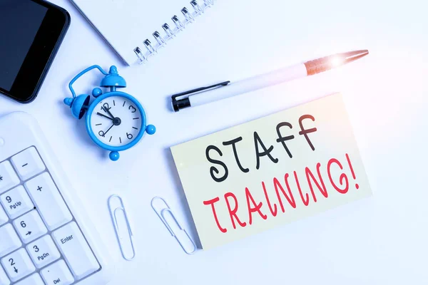 Text sign showing Staff Training. Conceptual photo program that helps employees learn specific knowledge Flat lay above computer mobile phone clock pencil and copy space note paper.