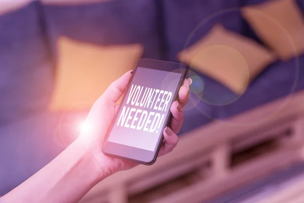 Writing note showing Volunteer Needed. Business photo showcasing asking demonstrating to work for organization without being paid woman using smartphone and technological devices inside the home.