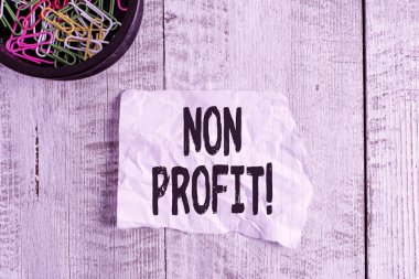 Non Profit 'i gösteren kavramsal el yazısı. İş fotoğraflarının sergilenmesi öncelikli olarak kâr kuruluşu için yapılmadı ya da yürütülmedi. Kırışıklık kağıdı ve mukavva, ahşap arka fonun üzerine yerleştirildi..