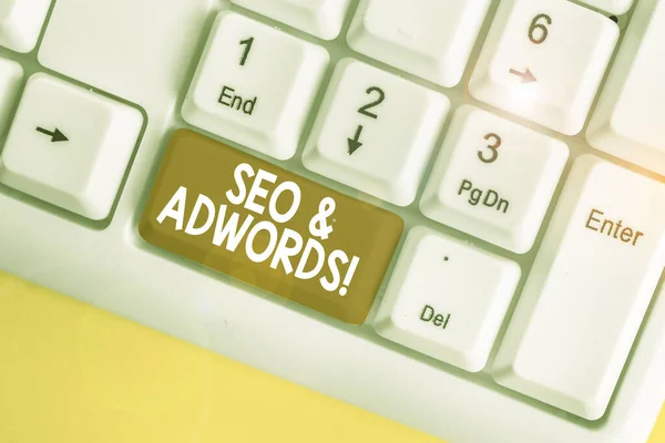 Text sign showing Seo And Adwords. Conceptual photo they are main tools components of Search Engine Marketing White pc keyboard with empty note paper above white background key copy space. — Stock Photo, Image