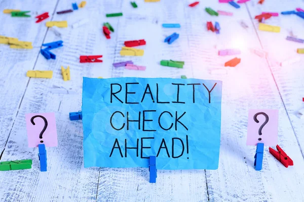 Tekst pisma Reality Check Ahead. Znaczenie pojęcia sprawia, że rozpoznają prawdę o sytuacjach lub trudnościach Spisane i kruche arkusze z spinaczami umieszczonymi na drewnianym stole. — Zdjęcie stockowe