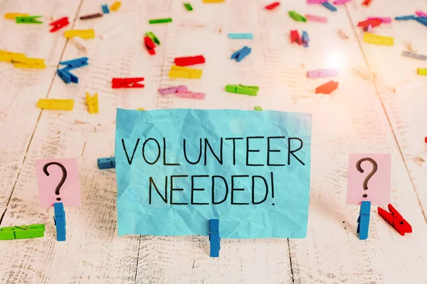 Handwriting text Volunteer Needed. Concept meaning need work for organization without being paid Scribbled and crumbling sheet with paper clips placed on the wooden table.