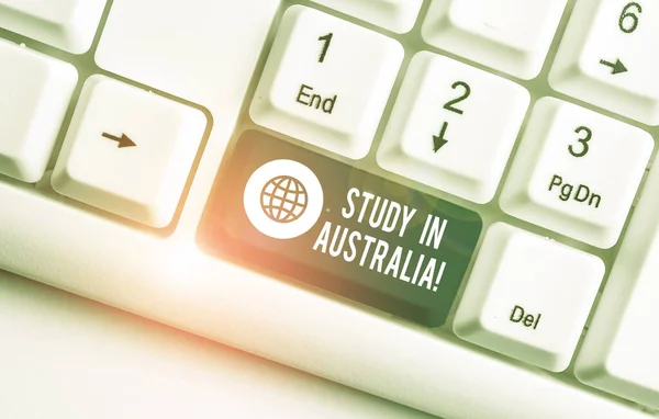 Woord schrijf tekst studie in Australië. Bedrijfsconcept om naar het buitenland te gaan bestel Voltooi uw studies wit PC-toetsenbord met lege notitie papier boven witte achtergrond sleutel kopiëren ruimte. — Stockfoto