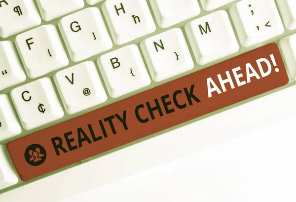 Escribir una nota que muestre Reality Check Ahead. Exhibición de fotos de negocios les hace reconocer la verdad sobre situaciones o dificultades Teclado de PC blanco con papel de nota sobre el fondo blanco . —  Fotos de Stock