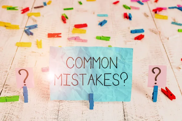 Handwriting text Common Mistakes question. Concept meaning repeat act or judgement misguided or wrong Scribbled and crumbling sheet with paper clips placed on the wooden table.