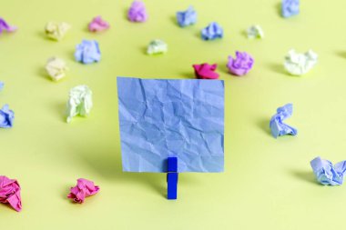 Dikdörtgen kare şekilli mandallı renkli kağıt ya da arka planda kağıt topu. Masanın etrafına renkli buruşuk notlar dağılmış. Ofis Malzemeleri Masada.