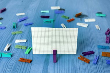 Dikdörtgen kare şekilli mandallı renkli kağıt ya da arka planda kağıt topu. Masanın etrafına renkli buruşuk notlar dağılmış. Ofis Malzemeleri Masada.