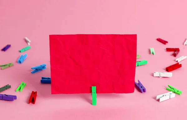 Rectángulo cuadrado en forma de papel coloreado con pinza de ropa o bola de papel en un fondo ligero. Nota arrugada colorida se extiende alrededor de la mesa. Suministros de oficina en un escritorio . —  Fotos de Stock