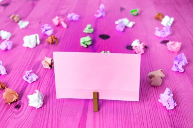 Dikdörtgen kare şekilli mandallı renkli kağıt ya da arka planda kağıt topu. Masanın etrafına renkli buruşuk notlar dağılmış. Ofis Malzemeleri Masada.