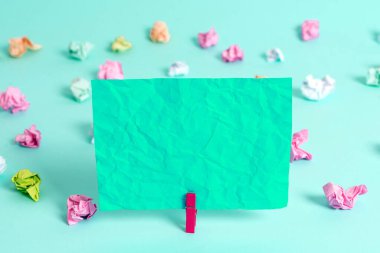 Dikdörtgen kare şekilli mandallı renkli kağıt ya da arka planda kağıt topu. Masanın etrafına renkli buruşuk notlar dağılmış. Ofis Malzemeleri Masada.