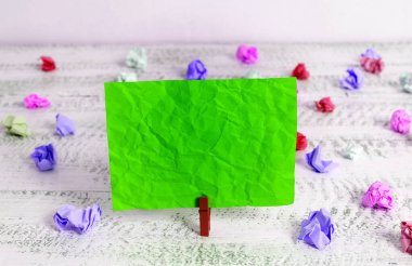 Dikdörtgen kare şekilli mandallı renkli kağıt ya da arka planda kağıt topu. Masanın etrafına renkli buruşuk notlar dağılmış. Ofis Malzemeleri Masada.