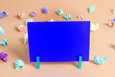 Dikdörtgen kare şekilli mandallı renkli kağıt ya da arka planda kağıt topu. Masanın etrafına renkli buruşuk notlar dağılmış. Ofis Malzemeleri Masada.