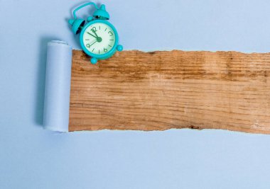 Çalar saati ve çivileri ahşap masanın üzerine yerleştirilmiş rulo şeklinde sökülmüş karton. Ahşap bir zemindeki kalın yırtık kağıt. Flat Lays Fotoğrafçılığı Düzenleme Sanatsal Yolu