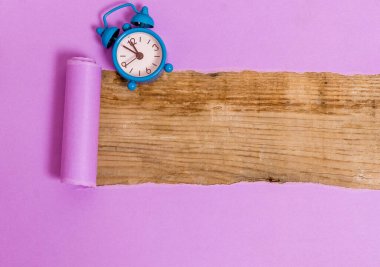 Çalar saati ve çivileri ahşap masanın üzerine yerleştirilmiş rulo şeklinde sökülmüş karton. Ahşap bir zemindeki kalın yırtık kağıt. Flat Lays Fotoğrafçılığı Düzenleme Sanatsal Yolu