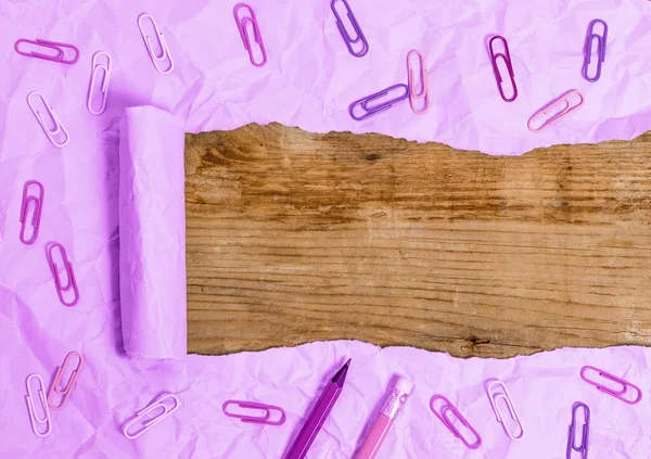 Carton déchiré roulé avec réveil et goupilles placées au-dessus de la table en bois. Papier épais déchiré sur fond de bois texturé. Manière artistique d'organiser la photographie de couches plates — Photo