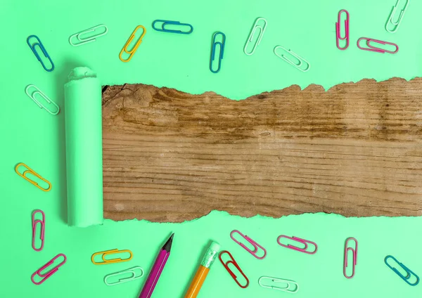 Cartón desgarrado laminado con reloj despertador y pasadores colocados diseñados por encima de la mesa de madera. Papel desgarrado grueso sobre un fondo de madera texturizada. Manera artística de organizar fotografías planas — Foto de Stock