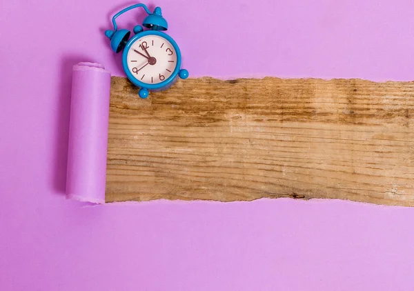 Cartone ondulato laminato con sveglia e spilli posizionati sopra il tavolo di legno. Carta spessa strappata su uno sfondo di legno strutturato. Modo artistico di organizzare piatti Laici Fotografia — Foto Stock