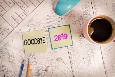El yazısı. Elveda 2019. Kavram demek, hoş geldin demek ve mutlu bir yeni yılı kutlamak demek ve merhaba 2020 yazma ekipmanı ve bilgisayar malzemeleri artı ahşap masanın üzerine yerleştirilmiş içecekler..