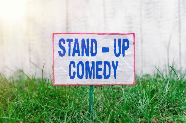 Stand-up Comedy 'yi gösteren bir mesaj. Kavramsal fotoğraf bir komedyenin komik hikayeler ezbere okuduğu bir çizgi roman. Kırışık bir kağıda yapışmış ve yeşil çimenli topraklara yerleştirilmiş..