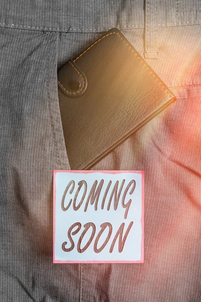 Writing note showing Coming Soon. Business photo showcasing an event that is bound to happen in the future or about to come Small wallet inside trouser front pocket near notation paper. — Stock Photo, Image