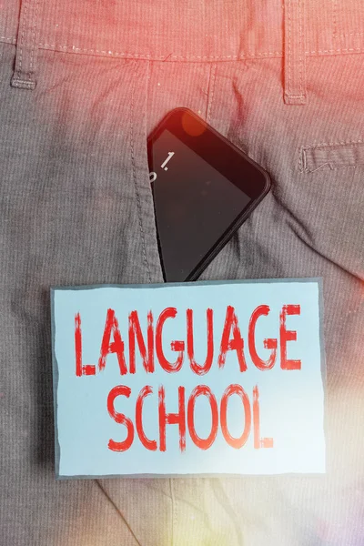 Handwriting text writing Language School. Concept meaning educational institution focusing on foreign languages Smartphone device inside formal work trousers front pocket near note paper.