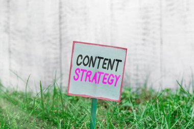 Kelime yazma içerik stratejisi. Önemli pazarlama yaklaşımı için ticari konsept alıcı çekmek için Düz boş kağıt çubuk ve yeşil çimenli araziye yerleştirilir.