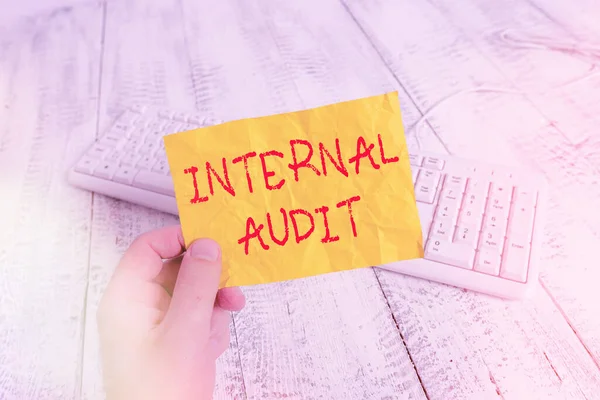 Text sign showing Internal Audit. Conceptual photo evaluates the objective assurance to improve a firm s is operation man holding colorful reminder square shaped paper white keyboard wood floor. — Stock Photo, Image