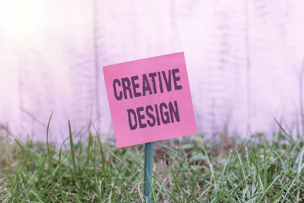 Writing note showing Creative Design. Business photo showcasing a visual element which satisfies its main objective Plain paper attached to stick and placed in the grassy land. — Stock Photo, Image