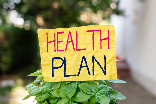 Word writing text Health Plan. Business concept for type of insurance that covers highcost medical services Plain empty paper attached to a stick and placed in the green leafy plants.
