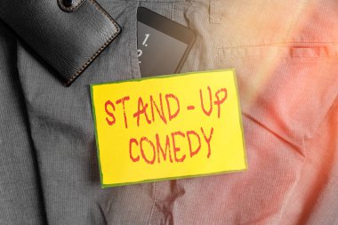 Stand-up Comedy 'yi gösteren kavramsal el yazısı. Bir komedyenin komik hikâyeler anlattığı bir iş fotoğrafı. Pantolonun ön cebinde cüzdanı olan bir akıllı telefon cihazı..