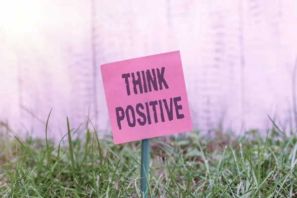 Schrijfbriefje met Think Positive. Zakelijke foto presentatie het creëren van gedachten die aanmoedigen en helpen bij het opladen van een individuele Plain papier bevestigd aan stok en geplaatst in het grasland. — Stockfoto